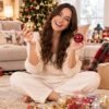 Joven sentada en el suelo mostrando bolas de Navidad brillantes en MegaSharkCo.