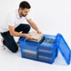 Joven organizando y guardando sus libros en una caja de almacenamiento azul de MegaSharkCo.