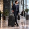Hombre con traje formal desplazandose por la terminal con maleta de mano negra MegaShark