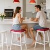Pareja desayunando en una cocina moderna con taburetes equipados con cojines rojos