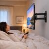 Televisor montado en la pared con soporte extensible orientado hacia la cama en una habitación